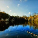 A scenic photo of Dosthill Quarry with the sun shining and lot's of greenery.