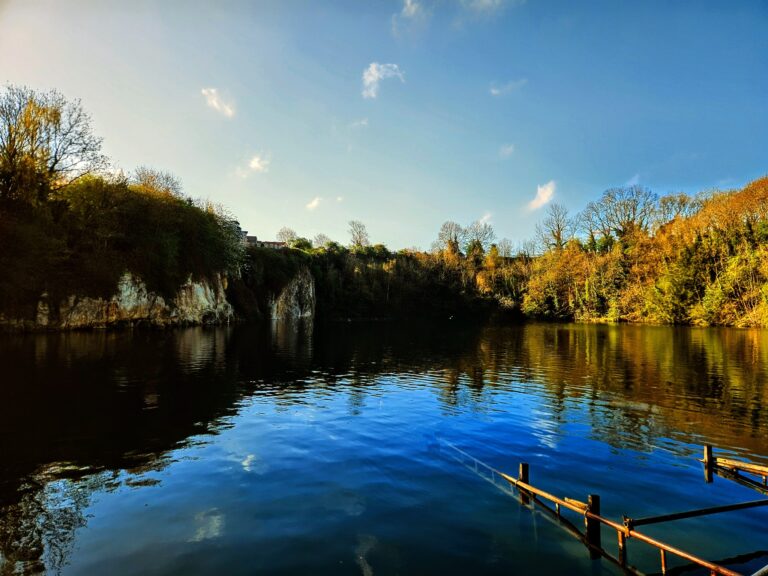 A scenic photo of Dosthill Quarry with the sun shining and lot's of greenery.