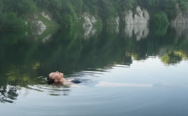 Female swimmer relaxing by floating on her back in a flooded quarry